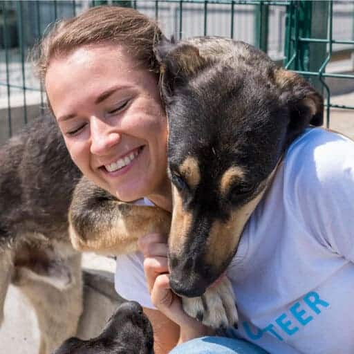 chien couleur feu qui enlace une bénévole pour représenter le fait de devenir dénévole  